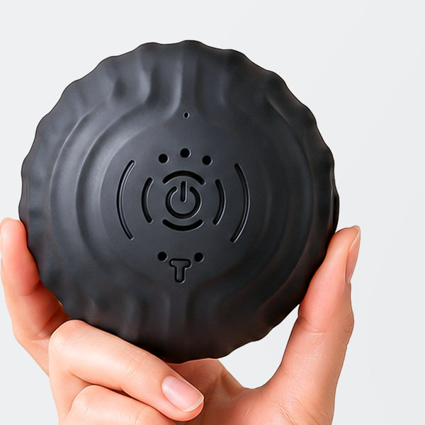 RECOVERO TRIGGER POINT ROLL vibrating massage ball held in one hand, showing the power button